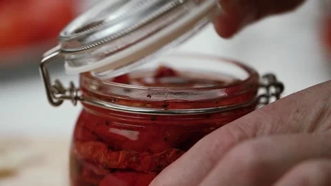 Chef closes lid of the finished dried tomatoes in glass jar a hook lock. macro. Video stock 254932746