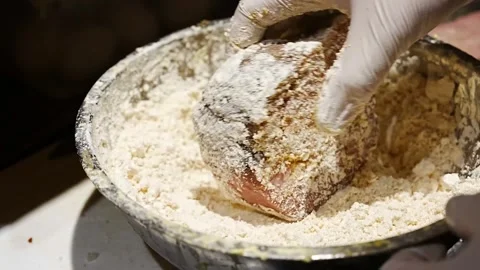 Chef coating roasted meat portions in flour and yellow batter before breading Stock Footage 345930350