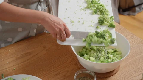 Chef combining ingredients for a quiche by adding broccoli to the filling Stock Footage 315596148