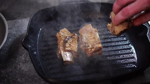 Chef cook adding more pieces of raw beef meat in hot steamy black grill frying Stock Footage 105896945