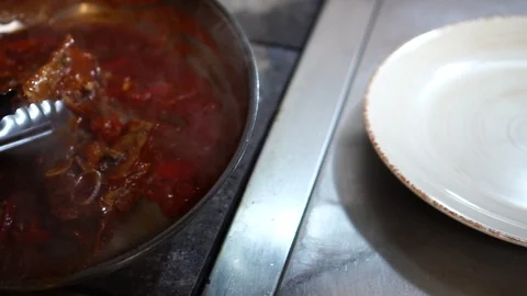 Chef cook arranging pork ribs meat slices in hot tomato sauce on clean white Stock Footage 106979075