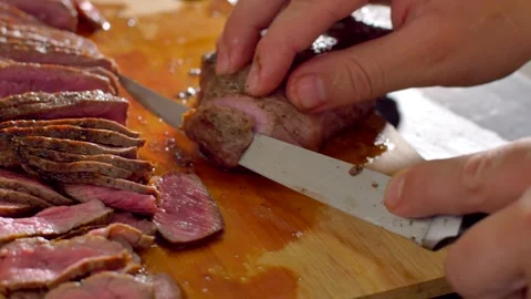 Chef cook cut beef with a knife on wooden board mid roasting Stock Footage 255979085