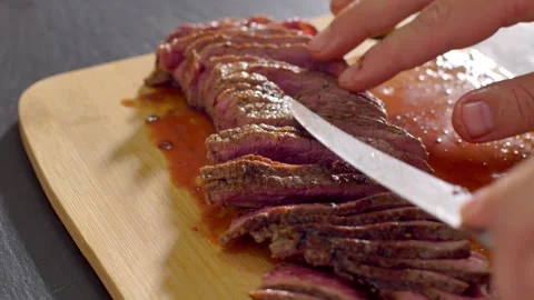 Chef cook cut beef with a knife on wooden board mid roasting Stock Footage 255979111