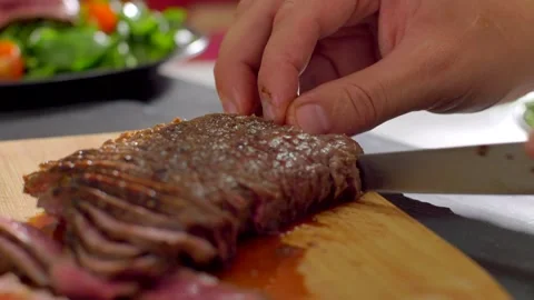 Chef cook cut beef with a knife on wooden board mid roasting Stock Footage 255979173