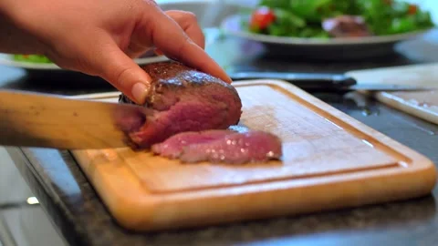 Chef cook cut beef with a knife on wooden board mid roasting Stock Footage 255979185