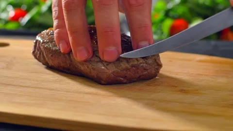 Chef cook cut beef with a knife on wooden board mid roasting Stock Footage 255979312