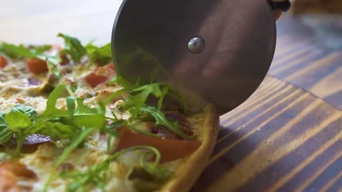 Chef cook cutting pizza with roller knife on wooden table in pizzeria. Close up Stock Footage 99169864