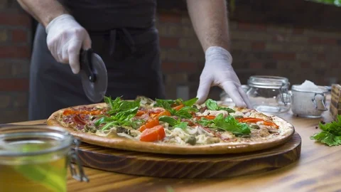 Chef cook cutting pizza with roller knife on wooden table in pizzeria. Close up 스톡 동영상 104399292