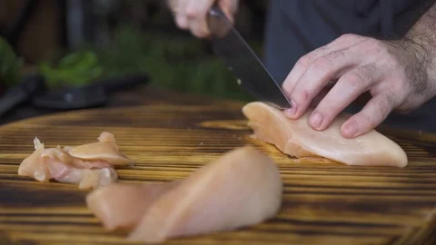 Chef cook cutting raw chicken fillet with knife on wooden table. Male hand Stock Footage 98769028