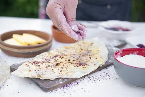 Chef, cook dusting flour on wrapped pita, taco lying on stylish, wooden board Stock Photos