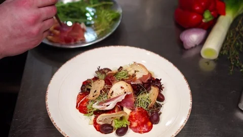 Chef cook hands arranging salad ingredients adding bacon on white plate for food Stock Footage 106977430