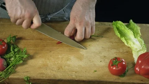 Chef cook professionally slicing chilli pepper with chefs knife on cutting board Stock Footage 76965246