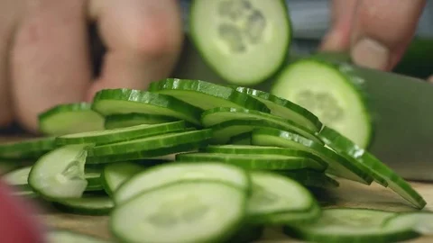 Chef cook professionally slicing a cucumber with a chef's knife on cutting board Stock Footage 76881593