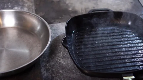 Chef cook putting raw beef meat slices on hot steamy grill frying pan in modern Stock Footage 105896839