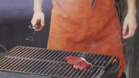 Chef Cook roasting beef meat on coal fire grill turning  Video stock 146791904