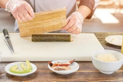 Chef cooked a sushi roll at kitchen. Stock Photos