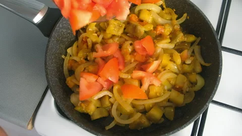 Chef cooking adding chopped tomatoes into pan with eggplant onion on kitchen. Stock Footage 312468354