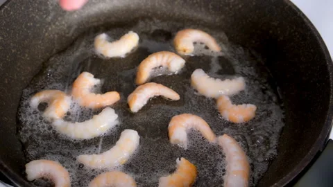 Chef cooking adding salt to frying shrimps in frying pan. Stock Footage 311889277