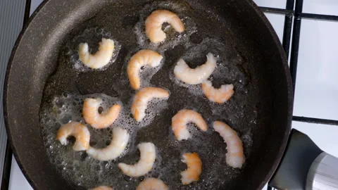 Chef cooking adding salt to frying shrimps in frying pan. Video stock 311889427