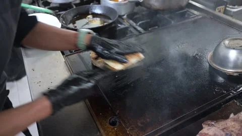 Chef cooking and plating grilled cod fish in a busy restaurant kitchen Stock-Footage 323792516