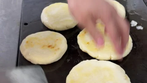 Chef cooking arepas on a hot griddle in a restaurant kitchen 動画素材 344100098