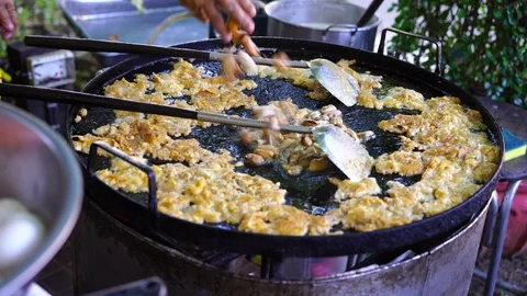 Chef cooking crispy fried shell pancake or oyster omelette (Hoi Tod) on big pan  Stock Footage 128409368