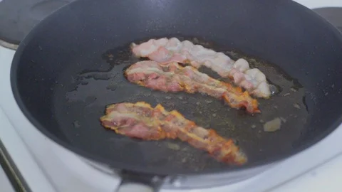 Chef cooking delicious crispy bacon stipes for breakfast, rich in fat and colour Stock Footage 128984098