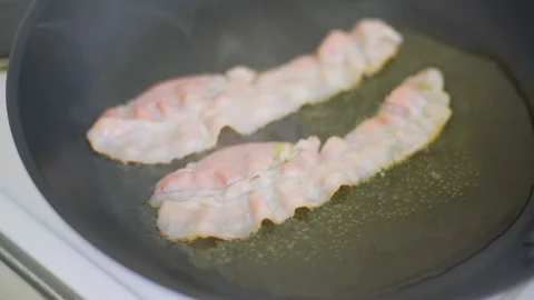 Chef cooking delicious crispy bacon stipes for breakfast, rich in fat and colour Stock Footage 128984101