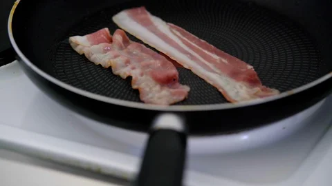 Chef cooking delicious crispy bacon stipes for breakfast, rich in fat and colour Stock Footage 128984564