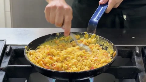 Chef cooking delicious scrambled eggs in a pan Видео 344100172