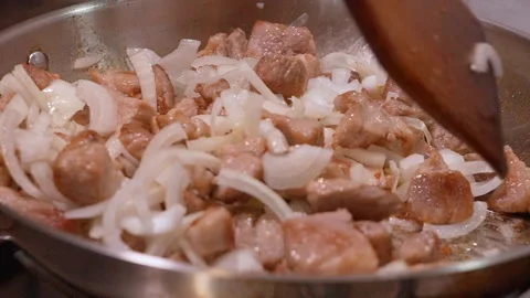 Chef cooking diced pork with sliced onions in a frying pan 動画素材 334152695