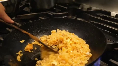 Chef Cooking Egg Fried Rice in a Traditional Black Wok Over a Gas Stove Burner Stock Footage 347689101