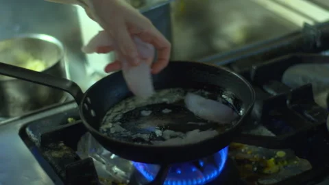 Chef cooking fish on pan hot restaurant kitchen flame stove 库存影片 330975898