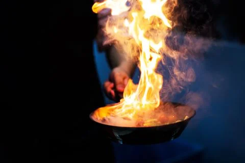 Chef cooking with flame in a frying pan on a kitchen stove.. Stock Photos