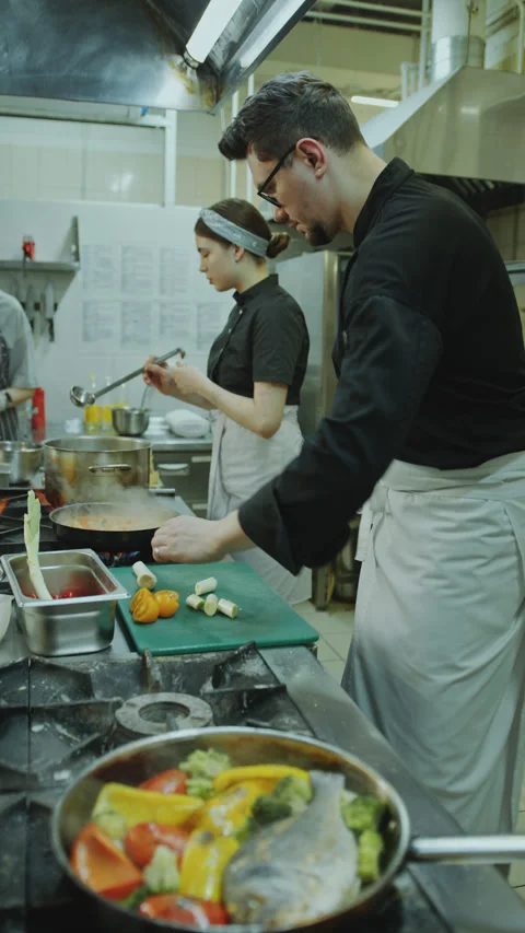 Chef Cooking Food with Female Apprentice in Restaurant Kitchen Stock Footage 270182535