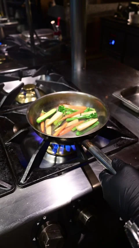 Chef cooking fresh vegetables in pan over gas stove Stock Footage 327255318