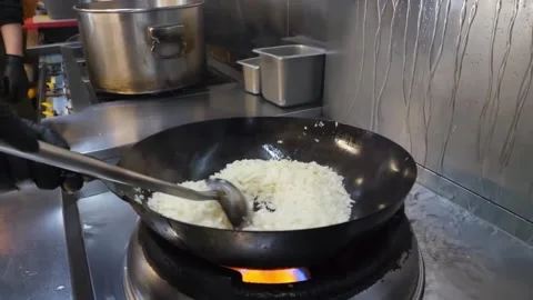 Chef cooking freshly prepared egg fried rice in a hot wok, tossing grains to ach Stock-Footage 332814527