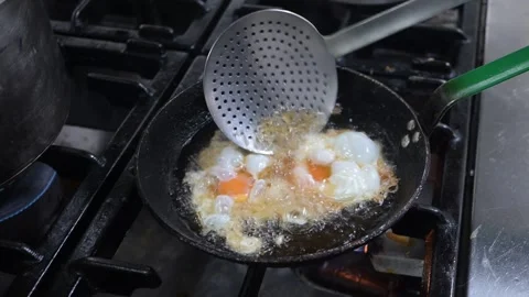 Chef cooking fried eggs in hot oil on a gas stove in a restaurant kitchen Stock Footage 323353765