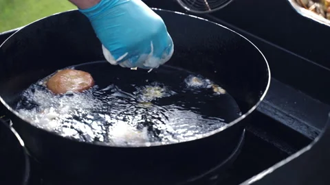 Chef in cooking gloves throwing liquid dough into hot sizzling oil in black pan Stock-Footage 171947290