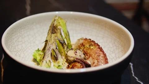 Chef cooking grilled octopus in modern restaurant with steamed vegetables Stock Footage 252756554