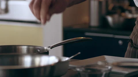 Chef cooking ingredients in a saucepan in interior kitchen with soft day lightin Stock Footage 199463522