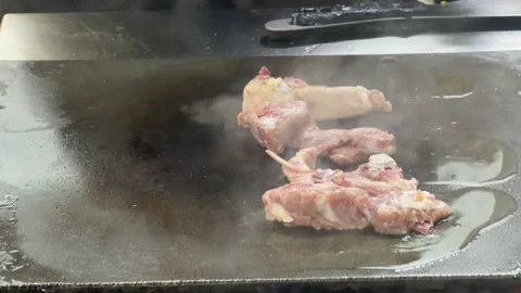 Chef cooking lamb chops on a hot griddle in a restaurant kitchen 動画素材 344100236