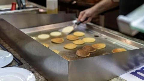 Chef Cooking Mini Pancakes on Flat Top Grill at Breakfast Stock Photos