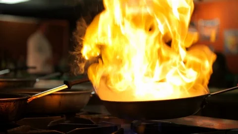 Chef. Cooking on a pan with restaurant guest in background. cu A Stock Footage 101700385