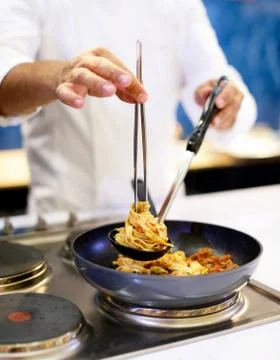 Chef cooking pasta, Chef serves spaghetti carbonara on the plate in the kitch Stock Photos