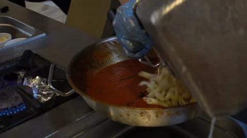 Chef is cooking pasta. Process of cooking pasta in tomato sauce with greens. Stock Footage 101898143