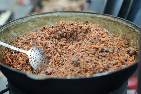 Chef cooking pilaf in a large cast iron cauldron. Preparing traditional rice  Stock Photos