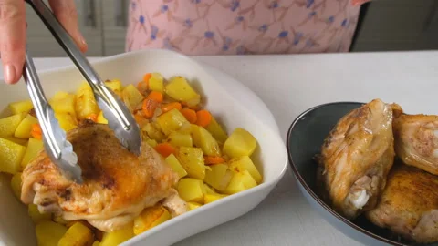 Chef cooking placing roasted chicken thighs on potatoes with carrots on kitchen. Stock Footage 317173511