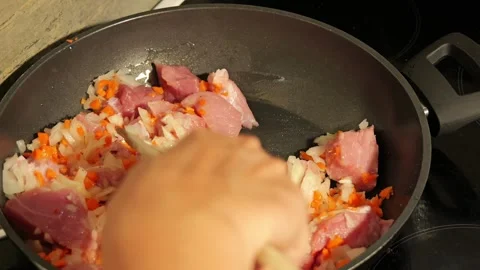 Chef cooking pork meat with onion and carrots in a frying pan Video stock 342758723