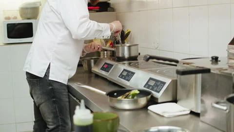 Chef cooking on professional kitchen, man ratating sauce in metalic pot with Stock Footage 266960167